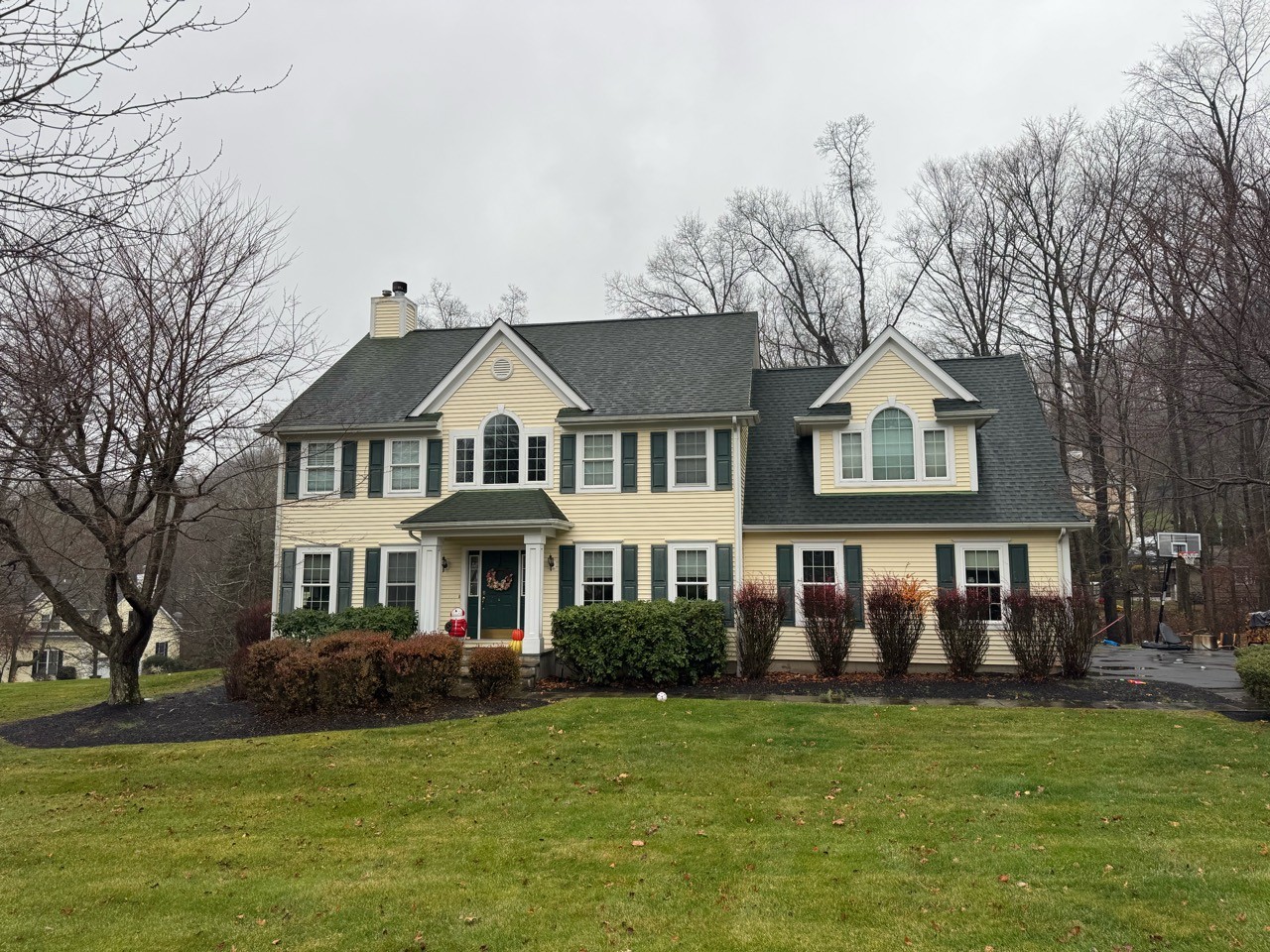 A separate yellow colonial home in daylight with its rooflines clearly visible